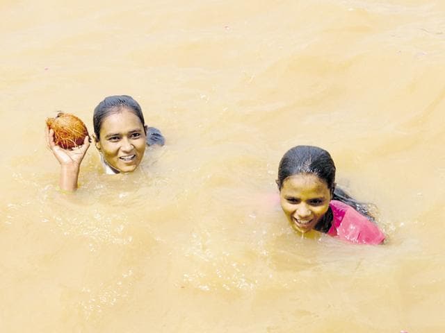 State swimming champions Hira and Diksha Silawat pull out a coconut from the Narmada river in Hoshangabad. Despite their creditable performance in the pool, the athletes haven’t received any assistance from the state government.(Praveen Bajpai/ HT PHOTO)