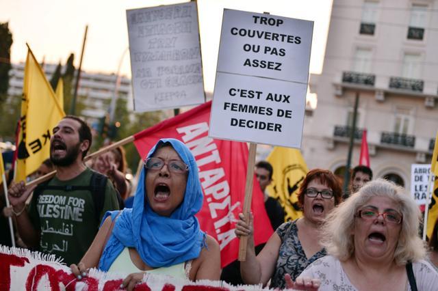 Women shout and hold placards reading messages such as "Too covered or not enough, it is up to women to decide" as they march towards the French embassy during a protest in Athens. (AFP Photo)