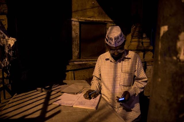 Babu looks at his phone as he prepares the account of his ice delivery near his makeshift ice shop. (AFP) Babu looks at his phone as he prepares the account of his ice delivery near his makeshift ice shop. (AFP)