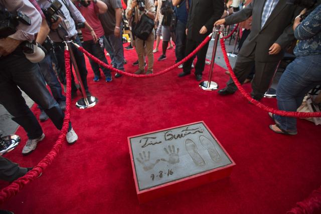 Photographers walk around the fresh handprints and footprints of director Tim Burton in the cement of the forecourt of the TCL Chinese Theatre. (AFP)