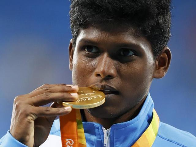 Mariyappan Thangavelu bites his gold medal as he poses for photographers on the podium. (REUTERS)
