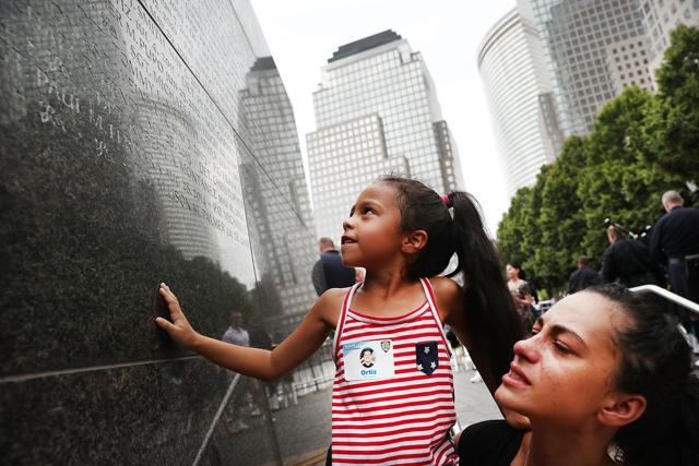 A woman holds up her daughter as she looks for her grandfather, New York city police officer Edwin Ortiz’s name at a wall commemorating fallen officers, on September 9, 2016. Families gathered at the wall to mark the 15th anniversary of the 9/11 attacks and the officers who were killed during and after the event. Detective Ortiz died from illnesses he contracted from inhaling toxic materials during the rescue and recovery operations at Ground Zero. (AFP)