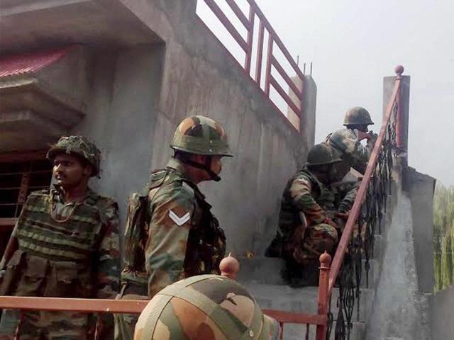 Security personnel take positions near a building where terrorists were holed up during an encounter in Poonch on Sunday.(PTI Photo)