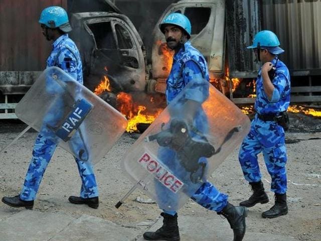 Members of the security forces make their way past burning lorries in Bengaluru, which were set on fire by protesters after SC ordered Karnataka to release 12,000 cubic feet of water per second every day from the Cauvery river to Tamil Nadu.(Reuters Photo)