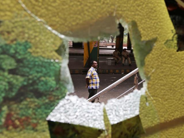 A man and policemen are seen through broken glass panes of a restaurant, run by people from Tamil Nadu, after it was vandalised by a mob during violence in Bengaluru. (AP Photo) 
