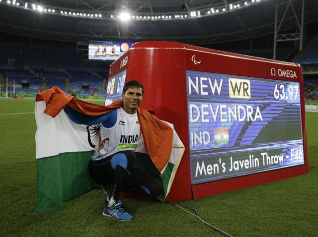 India's Devendra Jhajharia poses for a photo next to the scoreboard that shows his world record in the men's javelin throw F46 athletics event.(AP)