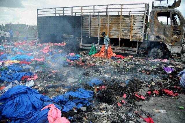 People search for valuables after a goods truck from Tamil Nadu was set on fire by protesters, at Nice Road in Bengaluru on Tuesday. (PTI)