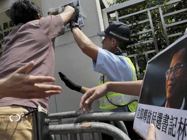 Hong Kong: A police officer tries to block protesters from pasting a picture of Wukan village's leader Lin Zuluan on the wall during a demonstration outside the Chinese central government's liaison office in Hong Kong on Wednesday. Police fired rubber bullets at villagers and arrested 13 people on Tuesday in an overnight crackdown to suppress demonstrations in the fishing village that became internationally known five years ago for protesting land seizures. (AP) Hong Kong: A police officer tries to block protesters from pasting a picture of Wukan village's leader Lin Zuluan on the wall during a demonstration outside the Chinese central government's liaison office in Hong Kong on Wednesday. Police fired rubber bullets at villagers and arrested 13 people on Tuesday in an overnight crackdown to suppress demonstrations in the fishing village that became internationally known five years ago for protesting land seizures. (AP)
