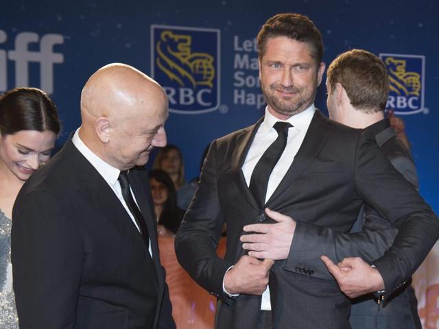 Actor Gerard Butler, centre, jokes around with Director Mark Williams, right, and actor Anupam Kher, left, as they arrive on the red carpet for the premiere of The Headhunter's Calling during the 2016 Toronto International Film Festival in Toronto. (AP)