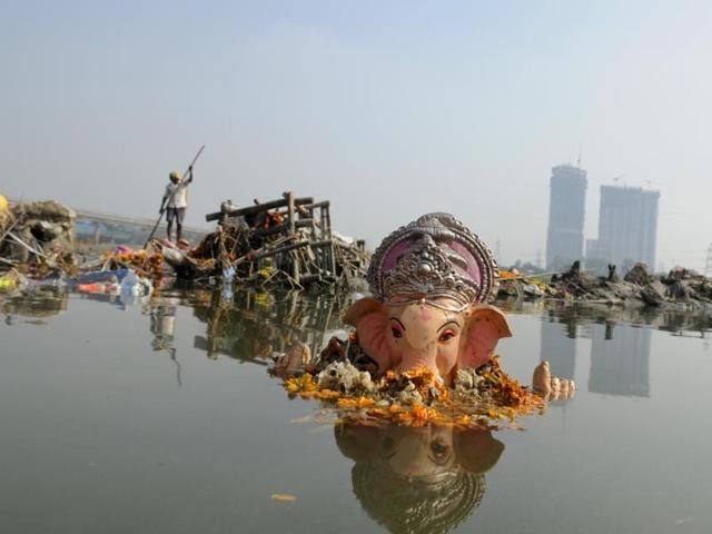 A man on a makeshift raft scouts for things that can be salvaged from the water along the banks of the Yamuna River near Kalindi Kunj. (Burhaan Kinu/HT PHOTO)