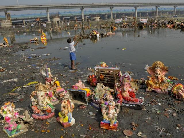 Scores of idols, lamps, flower garlands and other religious paraphernalia are salvaged from the river to be sold as scrap. (Burhaan Kinu/HT PHOTO)