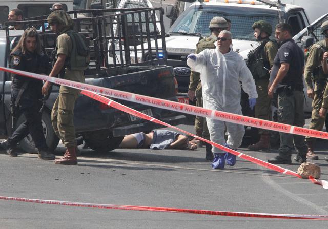 The body of Palestinian Fares Khadour, one of two assailants who rammed a car into a bus stop used by Israelis in the occupied southern West Bank, is seen on the ground as Israeli security personnel cordon off the site on Friday. The attack came shortly after Israeli police said they shot dead a Palestinian who tried to stab police officers in annexed east Jerusalem. (AFP) The body of Palestinian Fares Khadour, one of two assailants who rammed a car into a bus stop used by Israelis in the occupied southern West Bank, is seen on the ground as Israeli security personnel cordon off the site on Friday. The attack came shortly after Israeli police said they shot dead a Palestinian who tried to stab police officers in annexed east Jerusalem. (AFP)