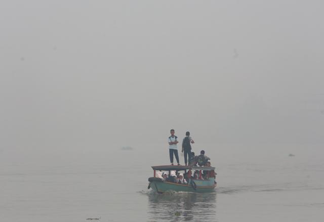 FILE - In this Thursday, Sept. 17, 2015 file photo, students ride on a boat on their way to school while haze from wildfires blanket the Musi River in Palembang, South Sumatra, Indonesia. Indonesian forest fires that choked a swath of Southeast Asia with a smoky haze for weeks in 2015 may have caused more than 100,000 premature deaths, according to new research. (AP) FILE - In this Thursday, Sept. 17, 2015 file photo, students ride on a boat on their way to school while haze from wildfires blanket the Musi River in Palembang, South Sumatra, Indonesia. Indonesian forest fires that choked a swath of Southeast Asia with a smoky haze for weeks in 2015 may have caused more than 100,000 premature deaths, according to new research. (AP)