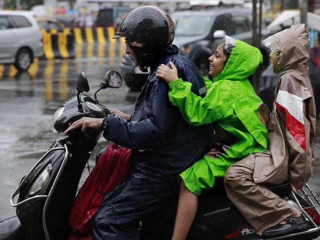 Schoolgirls ride home on a scooter in the rain in Mumbai. (AP) Schoolgirls ride home on a scooter in the rain in Mumbai. (AP)
