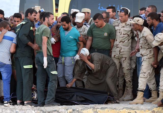 Egyptian policemen and medics stand over a body of a migrant along the shore in the Egyptian port city of Rosetta on September 21, 2016, during a search operation after a boat carrying migrants capsized in the Mediterranean. (AFP) Egyptian policemen and medics stand over a body of a migrant along the shore in the Egyptian port city of Rosetta on September 21, 2016, during a search operation after a boat carrying migrants capsized in the Mediterranean. (AFP)
