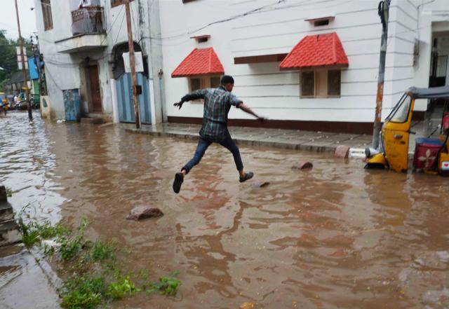 Man tries to cross a waterlogged street in Hyderabad on Thursday. (PTI) Man tries to cross a waterlogged street in Hyderabad on Thursday. (PTI)