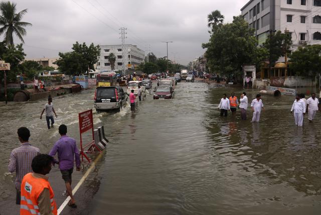 Vehicles and people navigate their way through a waterlogged street in Hyderabad. (AP) Vehicles and people navigate their way through a waterlogged street in Hyderabad. (AP)