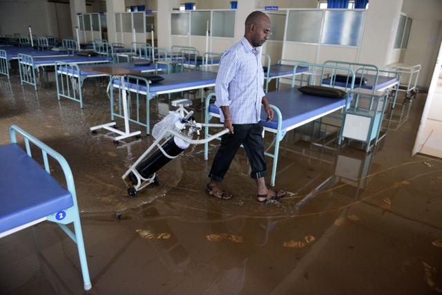 A memebr of the housekeeping staff moves an oxygen cylinder through a flooded ward of a private hospital, following heavy rain in Suraram. (AFP) A memebr of the housekeeping staff moves an oxygen cylinder through a flooded ward of a private hospital, following heavy rain in Suraram. (AFP)