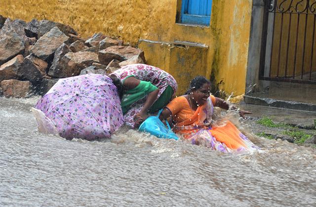 Women slip in water on a flooded street amidst heavy rains in Hyderabad . (AFP) Women slip in water on a flooded street amidst heavy rains in Hyderabad . (AFP)