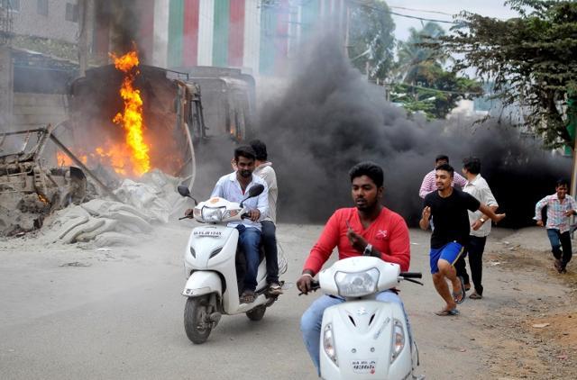 Men make their way past a burning lorry in Bengaluru. (Reuters File Photo) Men make their way past a burning lorry in Bengaluru. (Reuters File Photo)