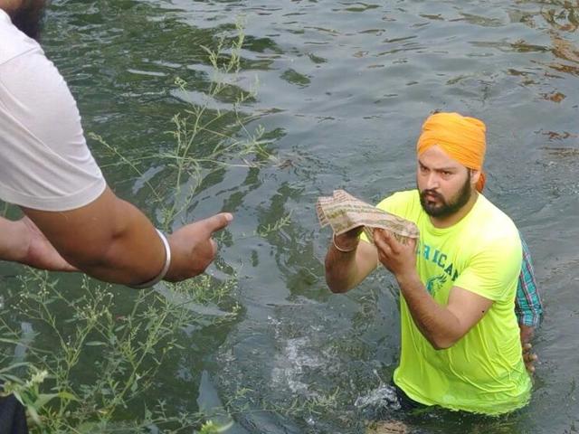 A group of men entered the canal to recover all pages.(Pardeep Pandit/HT Photo)