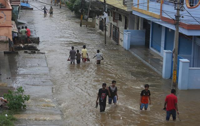 Children wade through a waterlogged street as it rains on the outskirts of Hyderabad. (AP Photo)