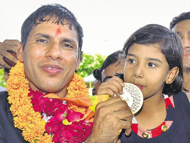 Rio Paralympics gold medallist Devendra Jhajharia with his daughter at Jaipur International Airport in Jaipur on Saturday. Jhajharia had promised his daughter that he would bag a gold if she tops her lower kindergarten exam.(Prabhakar Sharma/HT photo)