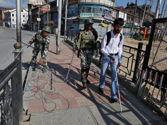 A policeman steers a visually impaired man clear of concertina wire laid on a pavement during curfew in Srinagar. (Danish Ismail/REUTERS) A policeman steers a visually impaired man clear of concertina wire laid on a pavement during curfew in Srinagar. (Danish Ismail/REUTERS)