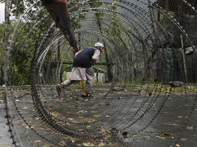 A Kashmiri man ducks to cross a barbed iron barricade wire near a military base at Braripora, near the de facto border in Kashmir on September 21, 2016. Kashmir has been in turmoil for the past two months, with civilians championing pro-independence calls. The violence was sparked by the July 8 killing of militant commander Burhan Wani in an encounter with soldiers. Since then, Kashmir has been paralysed by a curfew and separatist-called shutdown. (Mukhtar Khan/AP) A Kashmiri man ducks to cross a barbed iron barricade wire near a military base at Braripora, near the de facto border in Kashmir on September 21, 2016. Kashmir has been in turmoil for the past two months, with civilians championing pro-independence calls. The violence was sparked by the July 8 killing of militant commander Burhan Wani in an encounter with soldiers. Since then, Kashmir has been paralysed by a curfew and separatist-called shutdown. (Mukhtar Khan/AP)