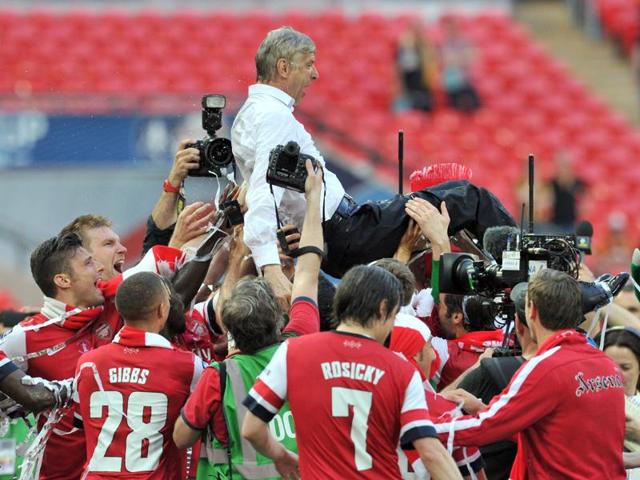 Arsenal players carry their French manager Arsene Wenger as they celebrate after winning the English FA Cup final match against Hull City at Wembley Stadium in London on May 17, 2014. (AFP File Photo)