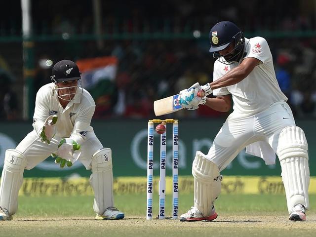 India's Rohit Sharma, center, raises bats after scoring fifty runs on the fourth day.(AP Photo)