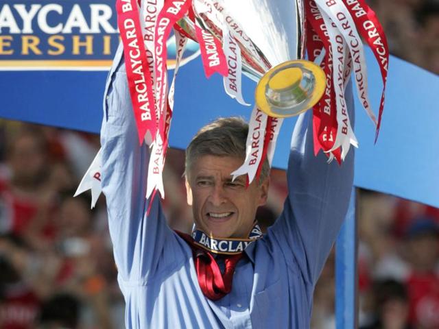 Arsenal manager Arsene Wenger holds up the Premiership trophy after winning the Premiership title and defeating Leicester City on 15 May, 2004 at Highbury in London. (AFP File Photo)