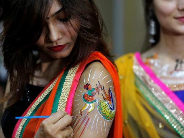 A girl paints on her arm a dancing couple performing Garba, the Gujarati folk dance. What are you doing to make this Navratri special? (REUTERS) A girl paints on her arm a dancing couple performing Garba, the Gujarati folk dance. What are you doing to make this Navratri special? (REUTERS)