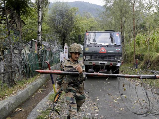 An Indian army soldier lifts an iron barricade to allow a vehicle to drive out of a military base at Braripora, near the de facto border.(AP Photo)