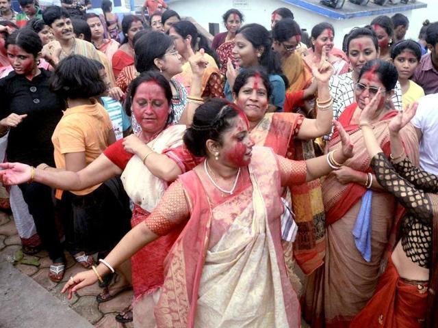 Married women in red sarees with red borders with vermillion splashed all over the face provide the most traditional picture of immersion revelry. (HT Photo) Married women in red sarees with red borders with vermillion splashed all over the face provide the most traditional picture of immersion revelry. (HT Photo)