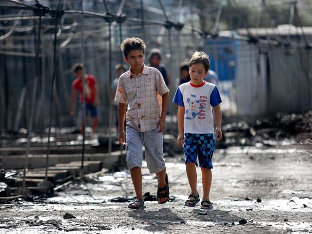 Children walk next to the remains of burned tents at the Moria migrant camp, after a fire that ripped through tents and destroyed containers during violence among residents, on the island of Lesbos, Greece on September 20.(REUTERS) Children walk next to the remains of burned tents at the Moria migrant camp, after a fire that ripped through tents and destroyed containers during violence among residents, on the island of Lesbos, Greece on September 20.(REUTERS)
