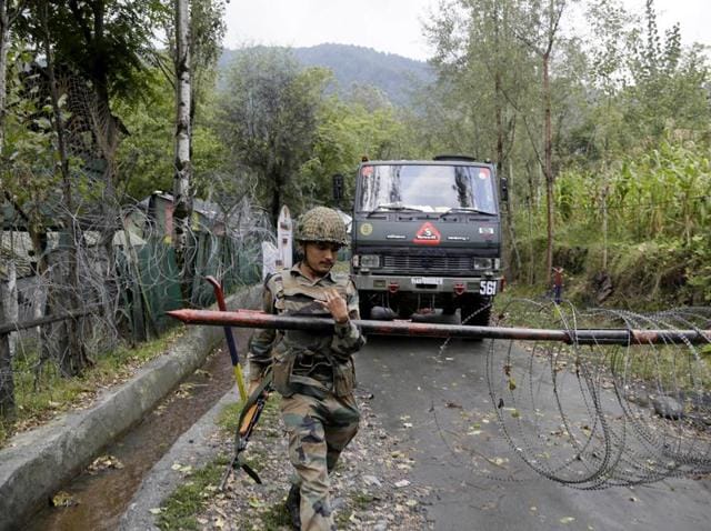 An army soldier lifts an iron barricade to allow a vehicle drive out of a military base at Braripora, near the de facto border dividing Kashmir between India and Pakistan, on September 21, 2016.(AP)