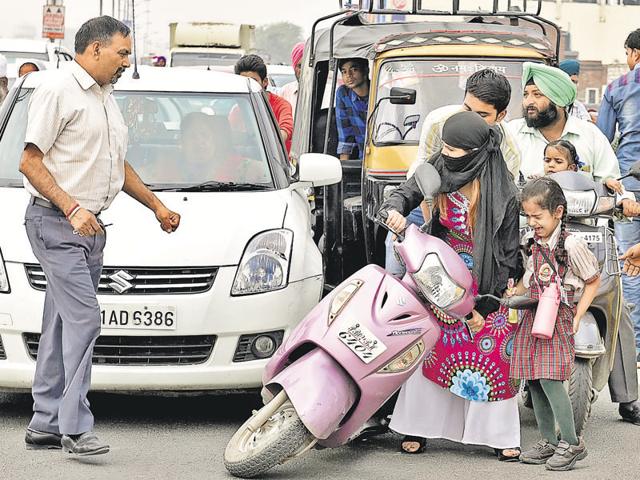 A woman stuck in the traffic chaos due to protest (right) by school vans and auto operators in Amritsar on Wednesday.(Gurpreet Singh/HT) A woman stuck in the traffic chaos due to protest (right) by school vans and auto operators in Amritsar on Wednesday.(Gurpreet Singh/HT)