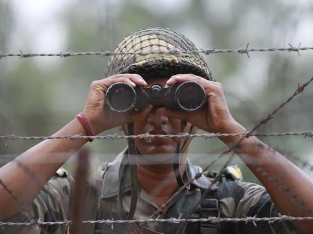 A BSF soldier looks at the Pakistan side of the border through a binocular at Ranbir Singh Pura, about 35km from Jammu.(AP file photo)