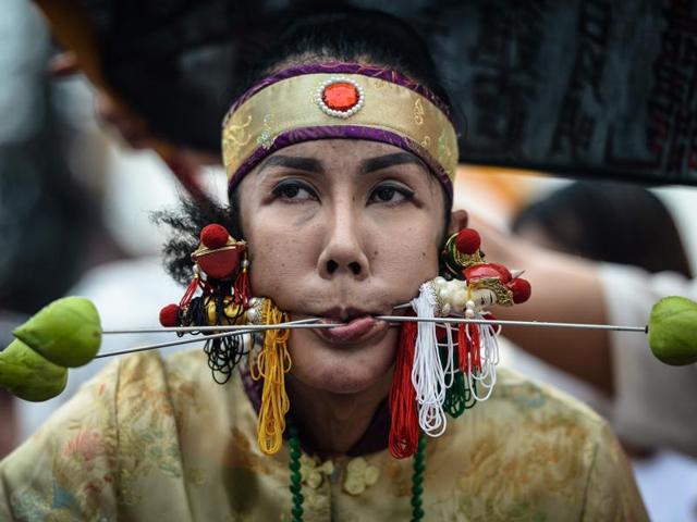 A devotee of the Nine Emperor Gods walks with needles through her face during the annual Phuket Vegetarian Festival in the southern province of Phuket, Thailand. Swords, axe handles, kebab skewers and even a model boat were just some of the objects placed in devotees’ pierced cheeks as southern Thailand’s vegetarian festival got under way. (AFP Photo) A devotee of the Nine Emperor Gods walks with needles through her face during the annual Phuket Vegetarian Festival in the southern province of Phuket, Thailand. Swords, axe handles, kebab skewers and even a model boat were just some of the objects placed in devotees’ pierced cheeks as southern Thailand’s vegetarian festival got under way. (AFP Photo)