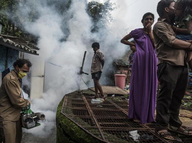 A BMC staffer conducts a fumigation near a well in a Mumbai locality. (Satish Bate/HT PHOTO)