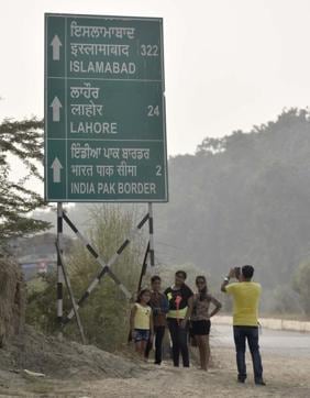 Not allowed to go up to the border, visitors click a photo with the board showing distances to Pakistani cities, near Attari on Monday. (Gurpreet Singh/HT Photo)