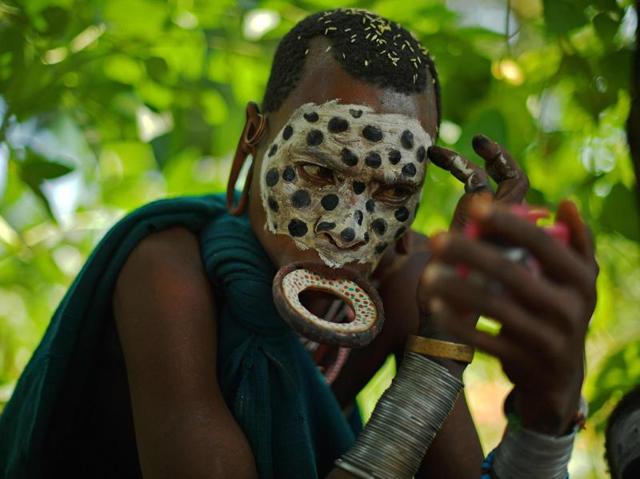 A woman from the Suri tribe wearing a lip plate paints her face near Kibbish on September 25, 2016. The Suri are a pastoralist Nilotic ethnic group in Ethiopia. The construction of the Gibe III dam, the third largest hydroelectric plant in Africa, and large areas of very ‘thirsty’ cotton and sugar plantations and factories along the Omo river are impacting heavily on the lives of tribes living in the Omo Valley who depend on the river for their survival and way of life. Human rights groups fear for the future of the tribes if they are forced to scatter, give up traditional ways through loss of land or ability to keep cattle as globalisation and development increases. (AFP) A woman from the Suri tribe wearing a lip plate paints her face near Kibbish on September 25, 2016. The Suri are a pastoralist Nilotic ethnic group in Ethiopia. The construction of the Gibe III dam, the third largest hydroelectric plant in Africa, and large areas of very ‘thirsty’ cotton and sugar plantations and factories along the Omo river are impacting heavily on the lives of tribes living in the Omo Valley who depend on the river for their survival and way of life. Human rights groups fear for the future of the tribes if they are forced to scatter, give up traditional ways through loss of land or ability to keep cattle as globalisation and development increases. (AFP)