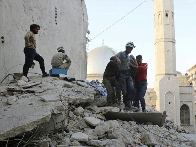 Civil Defense workers from the White Helmets carry a body as they walk on the rubles of a destroyed building after airstrikes hit the Bustan al-Basha neighbourhood in Aleppo.(Syrian Civil Defense White Helmets via AP)
