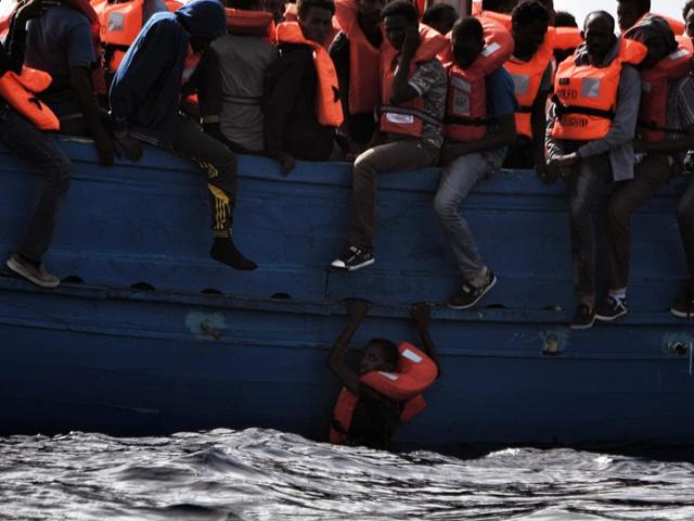 A migrant hangs from a boat as they wait to be rescued as they drift in the Mediterranean Sea some 20 nautical miles north off the coast of Libya. (AFP Photo) A migrant hangs from a boat as they wait to be rescued as they drift in the Mediterranean Sea some 20 nautical miles north off the coast of Libya. (AFP Photo)