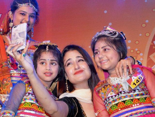 Bollywood actor Yuvika Choudhary clicks a selfie with kids who performed Garba at a Navratri function in Jabalpur. (PTI Photo)