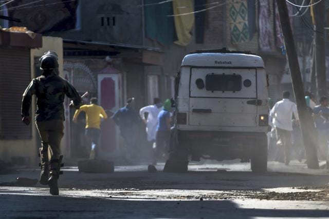 An Indian paramilitary soldier chases Kashmiri protesters during a protest in Srinagar on Friday. Authorities imposed a curfew in many parts of the Indian-controlled Kashmir to prevent a protest march to the disputed Himalayan region's office of United Nations Military Observer Group in India and Pakistan (UNMOGIP) called by separatist leaders seeking end of Indian rule.(AP)