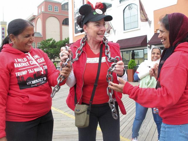 In this October 5, 2016 photo, Tina Condos, centre, greets fellow strikers outside the Trump Taj Mahal casino in Atlantic City while wearing chains to symbolise what she said were oppressive working conditions at the casino where she had worked since the day it opened in 1990. (AP) In this October 5, 2016 photo, Tina Condos, centre, greets fellow strikers outside the Trump Taj Mahal casino in Atlantic City while wearing chains to symbolise what she said were oppressive working conditions at the casino where she had worked since the day it opened in 1990. (AP)