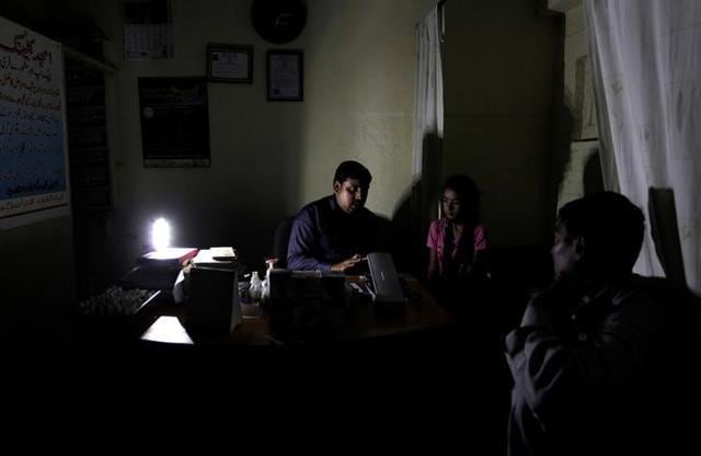 A homeopathic doctor speaks with the father of his patient at an infirmary during a power cut in Islamabad. (Reuters Photo) A homeopathic doctor speaks with the father of his patient at an infirmary during a power cut in Islamabad. (Reuters Photo)