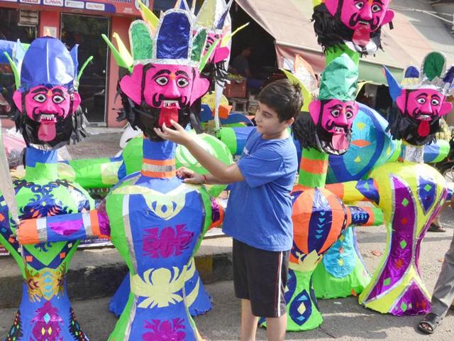 A child looking at the effigies of Ravan, Kumbhakaran and Meghnad at Lohgarh area in Amritsar on the eve of Dussehra on Monday.  (Sameer Sehgal/HT Photo) 